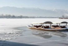 जम्मू-कश्मीर में भीषण सर्दी का प्रकोप, घाटी के मैदानी इलाकों में अब तक नहीं गिरी बर्फ कश्मीर में भीषण ठंड के कारण जमी हुई डल झील, बर्फ से ढकी शिकारा नावें और पृष्ठभूमि में हिमालयी पहाड़